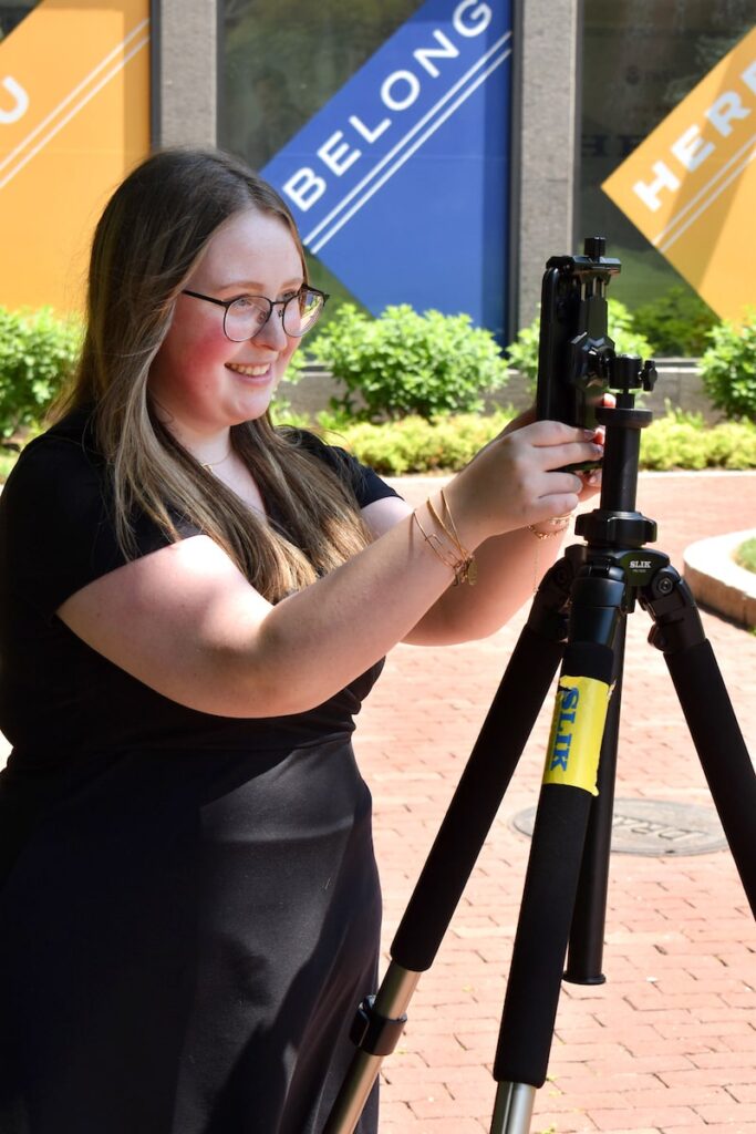 Jordan Millette, a Digital Marketing & Social Media student, setting up a camera on a tripod.