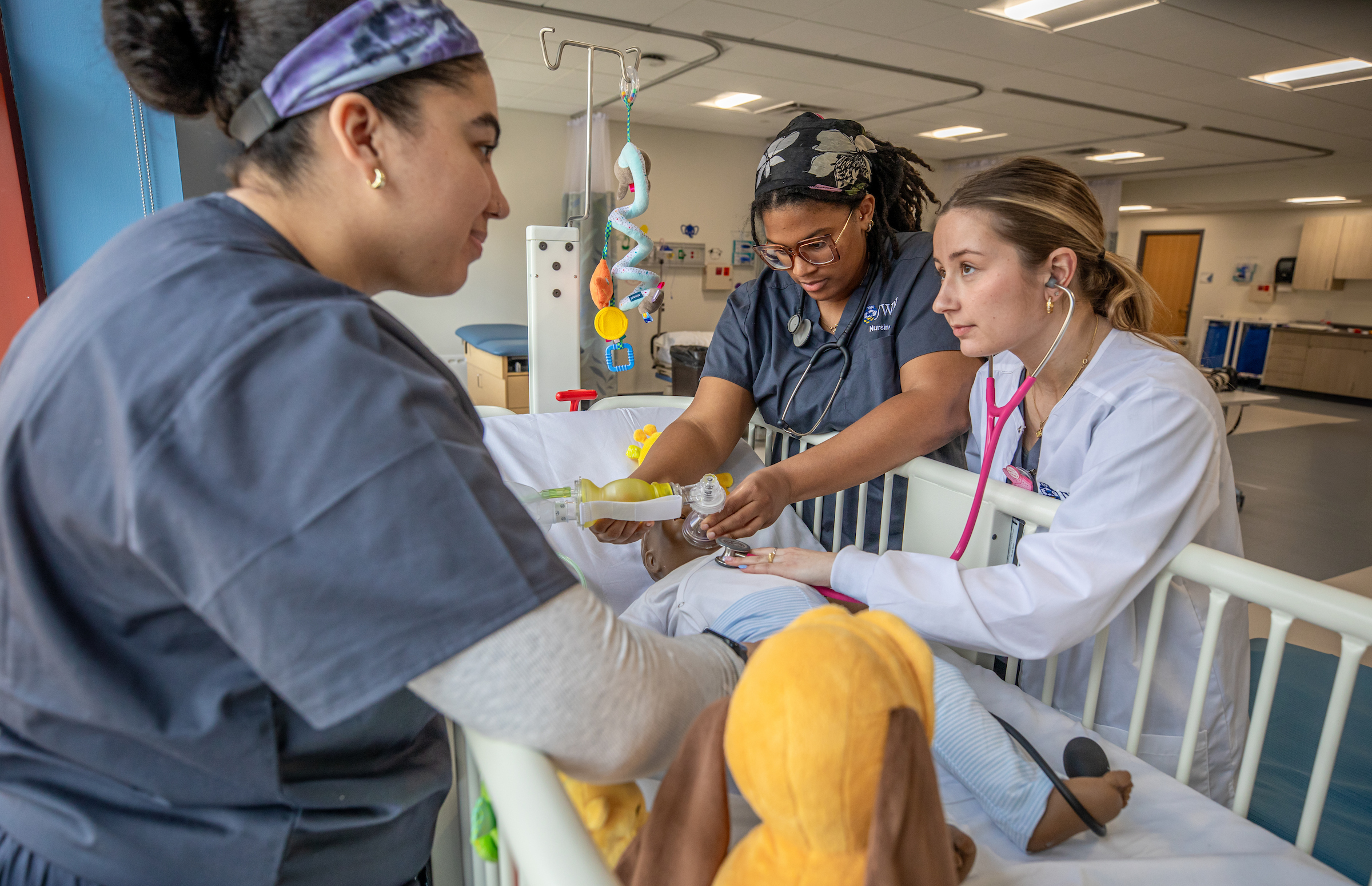 Three healthcare professionals collaborate to care for a child in a hospital bed, with one using a stethoscope and another handling medical equipment.