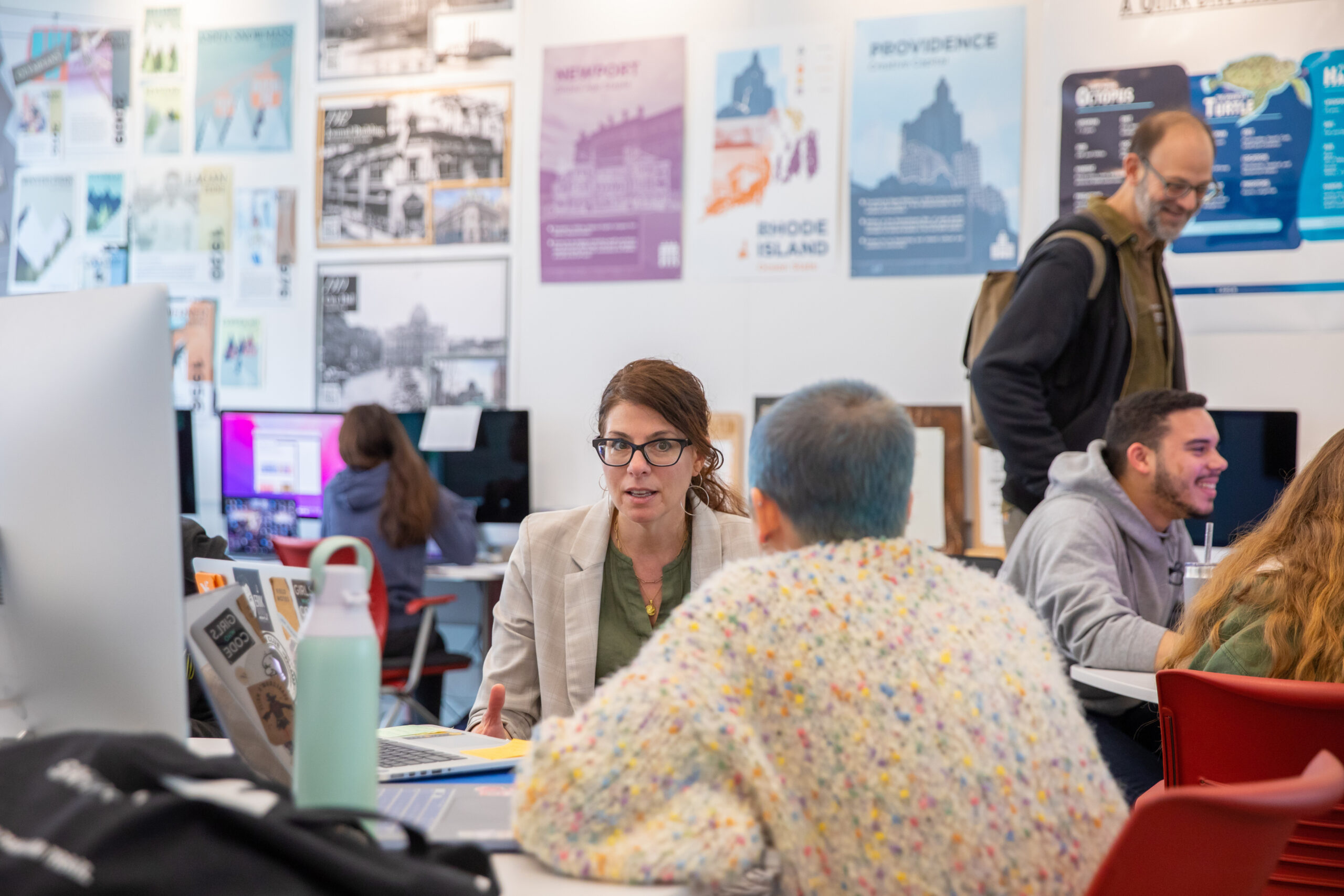 Classroom view with professor in center and several students surrounding