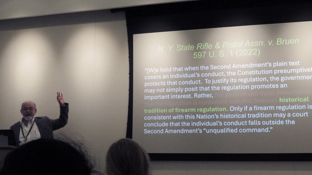 Professor stands in front of classroom with lecture pulled up about the constitution  