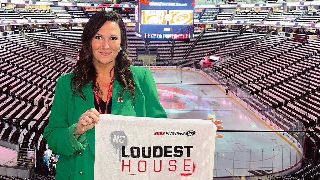 Samantha Lester holding a towel with empty hockey arena in the background