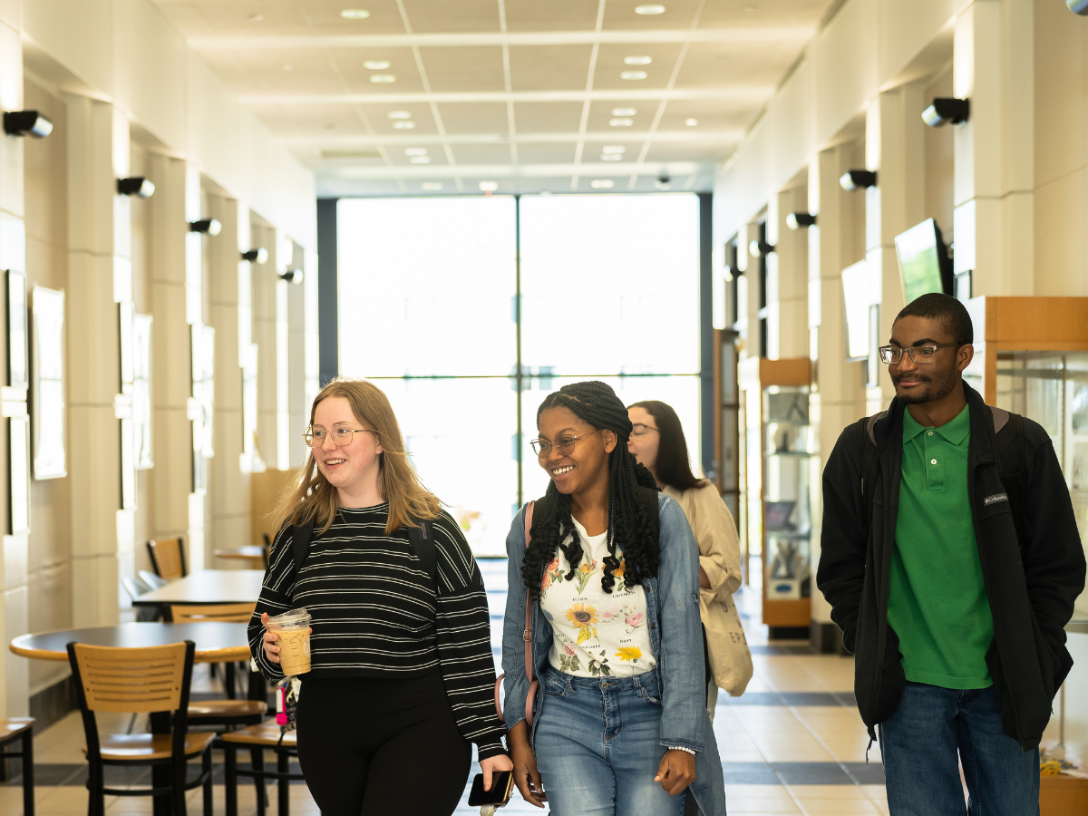 Three commuter students walk down a hallway.