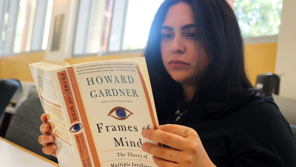 Student in black sweater reading a book