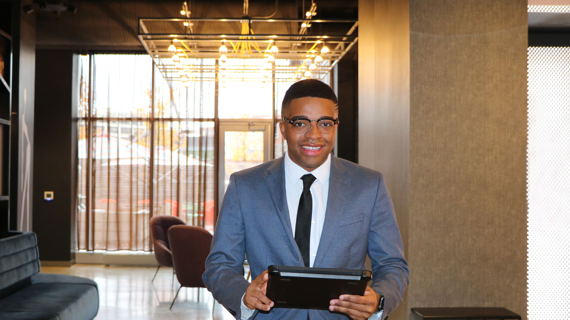 Male hospitality MBA student poses in suit in hallway