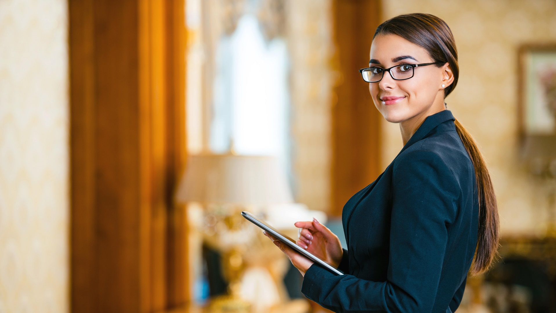 Woman with glasses holds tablet while working
