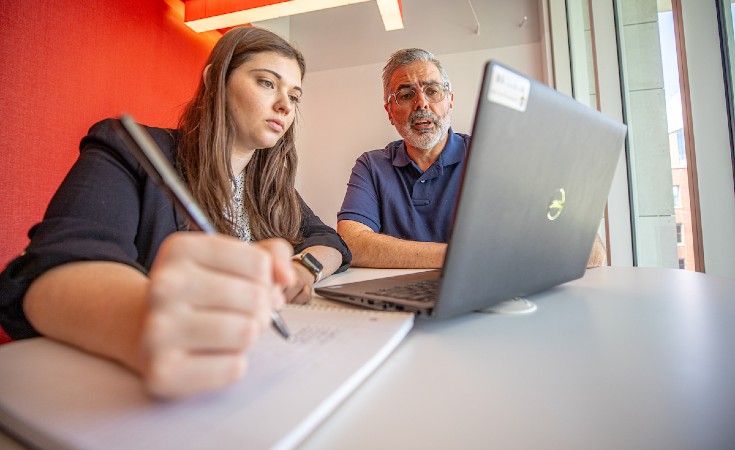 A student and professor looking at a laptop together