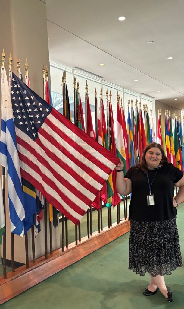 Student Rachel Meli stands next to an American flag