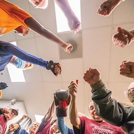 A circle of hands at Rock Steady Gym, where therapeutic workouts are helping those with Parkinson’s.