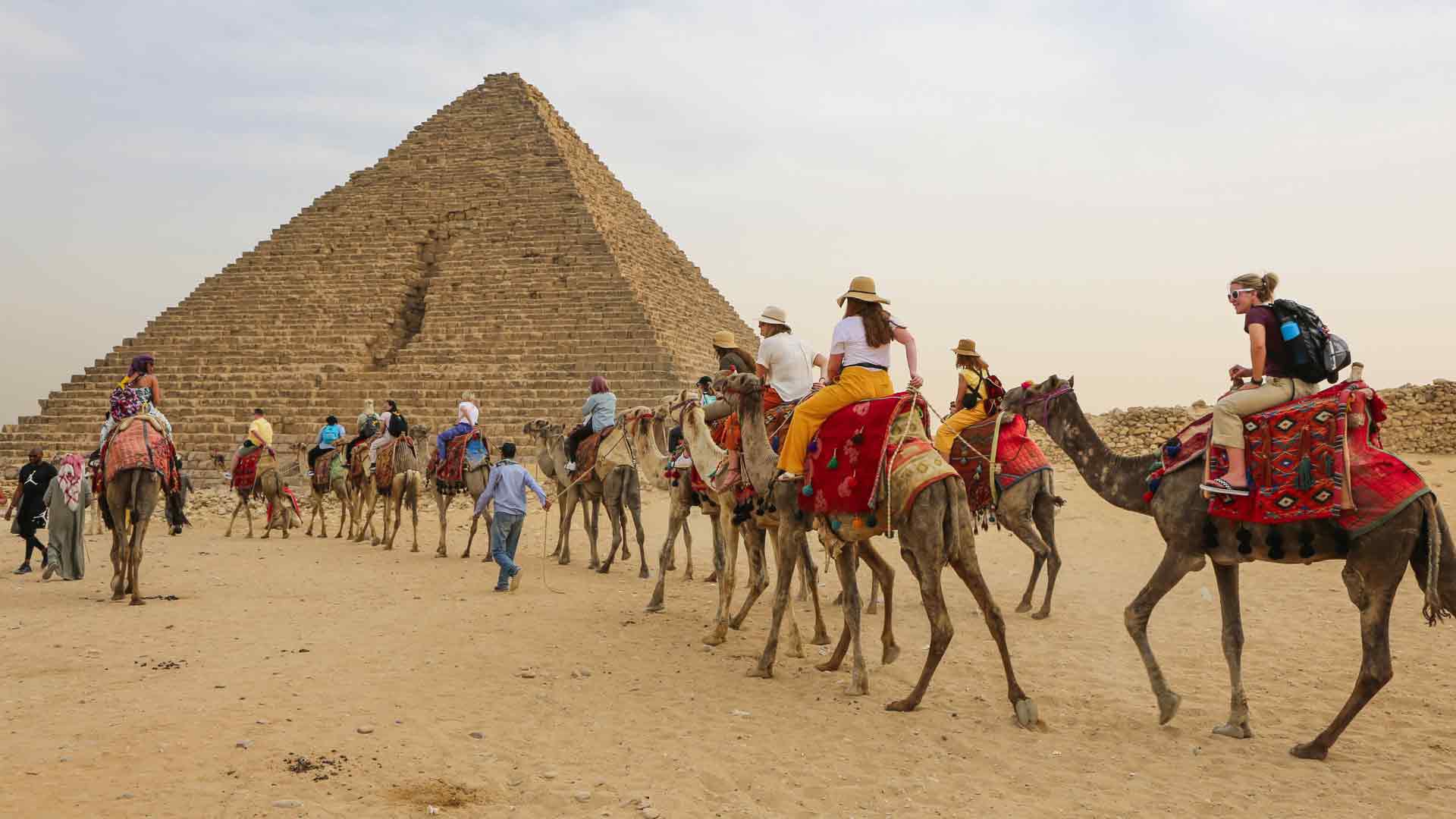 study abroad students riding camels in front of pyramids