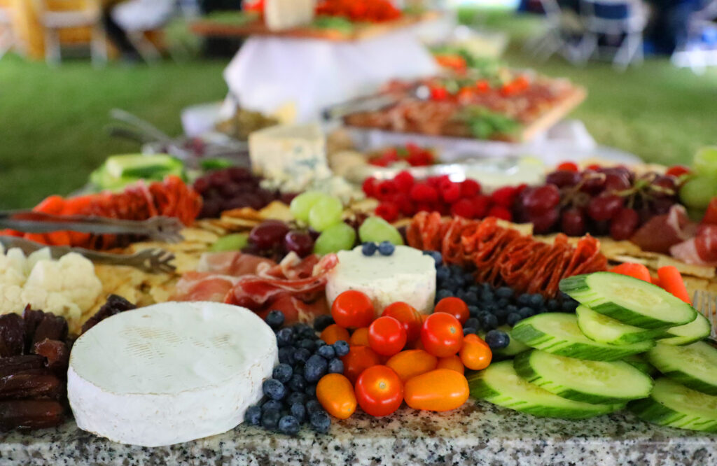 A vibrant charcuterie board featuring assorted cheeses, fresh fruits, vegetables, cured meats, and nuts.
