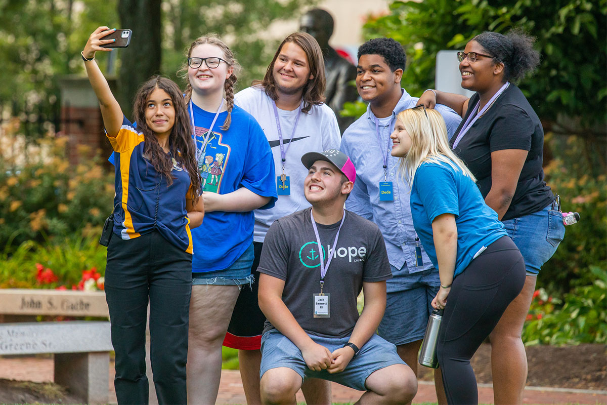 A group of prospective students pose together outdoors for a selfie.