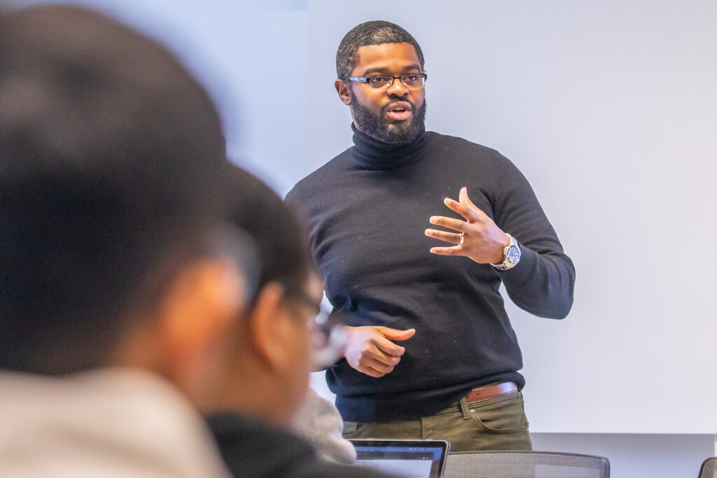 Man in black sweater lecturing a class