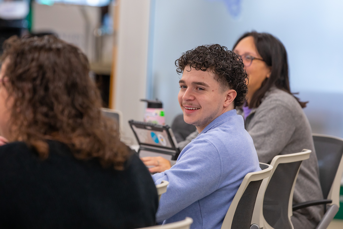 Male student smiles during classroom discussion 