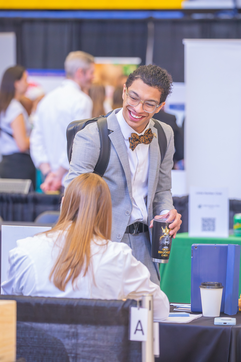Student in grey suit shaking hands with recruiter.