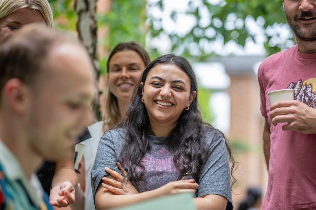A group of students smiling and laughing outside on the Providence campus.