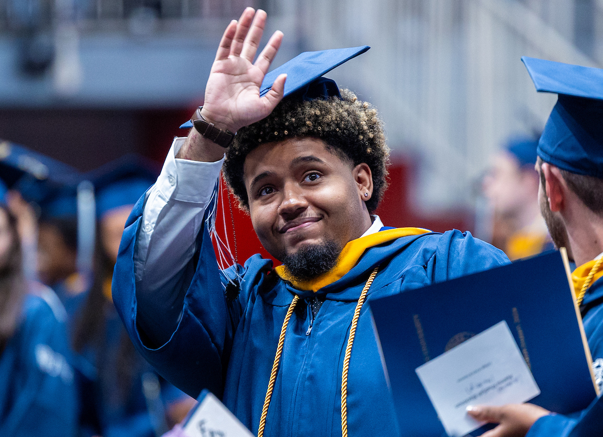 Male student waves to the crowd after receiving his diploma