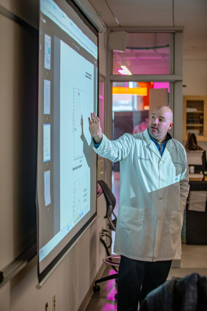 Professor in biology lab at projection wall