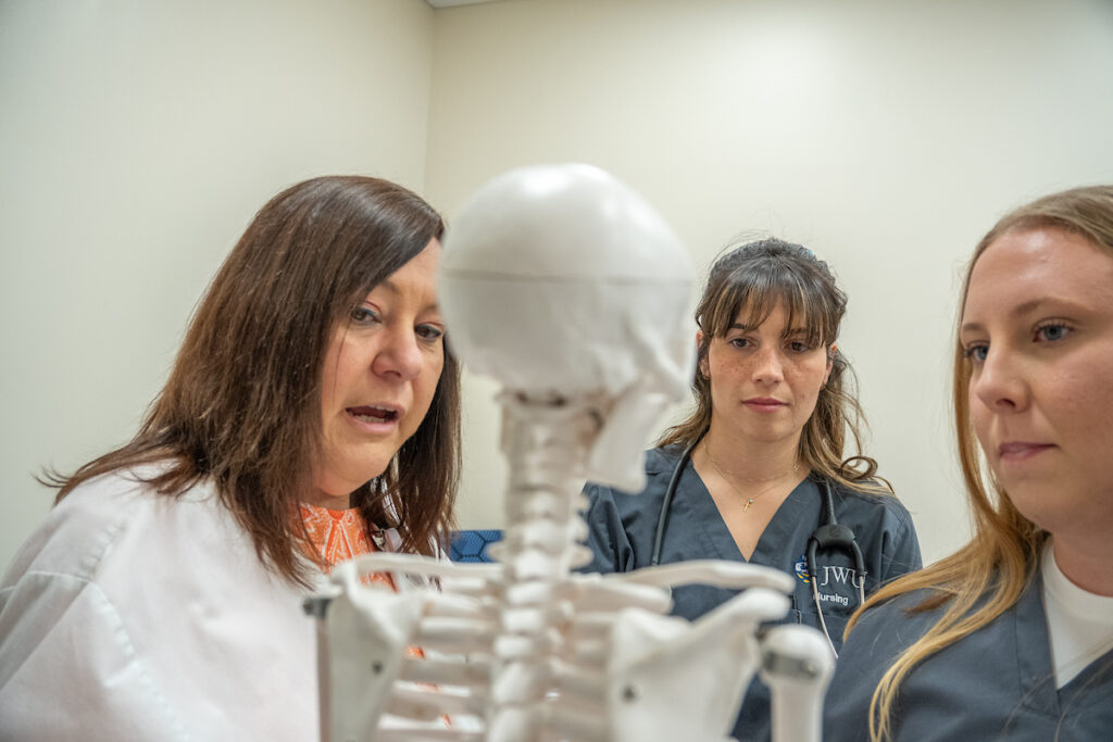 Nursing students and Professor looking at skeleton bone structure