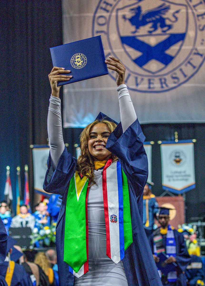 Female student holds up diploma after receiving it.