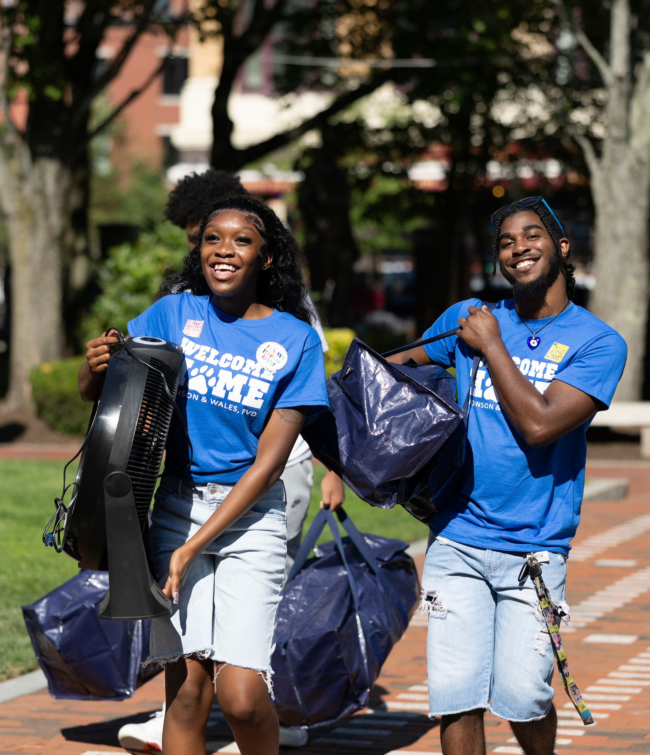 Students carry boxes and bins of supplies across campus during a welcome event.