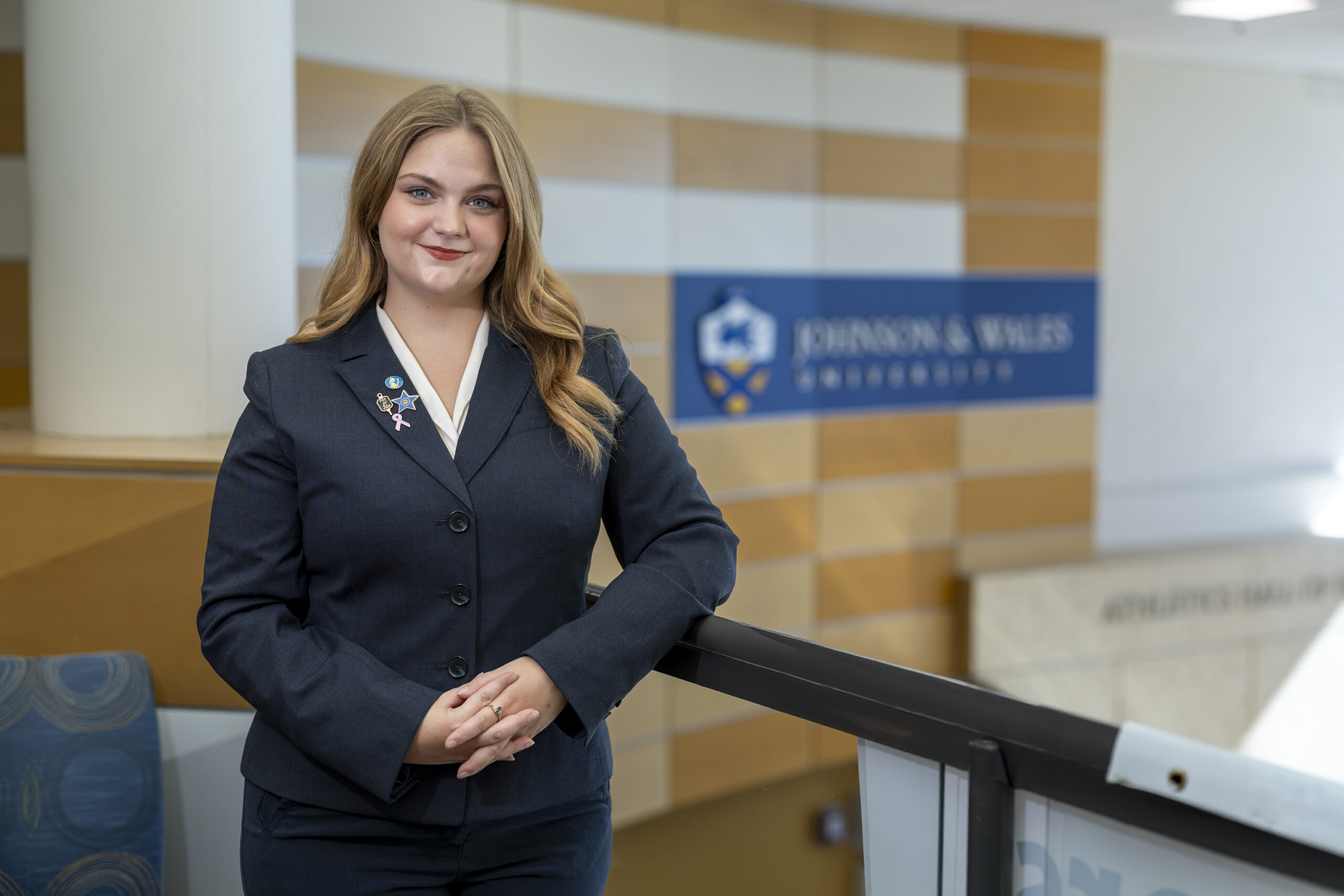A student standing next to a railing with a suit on.
