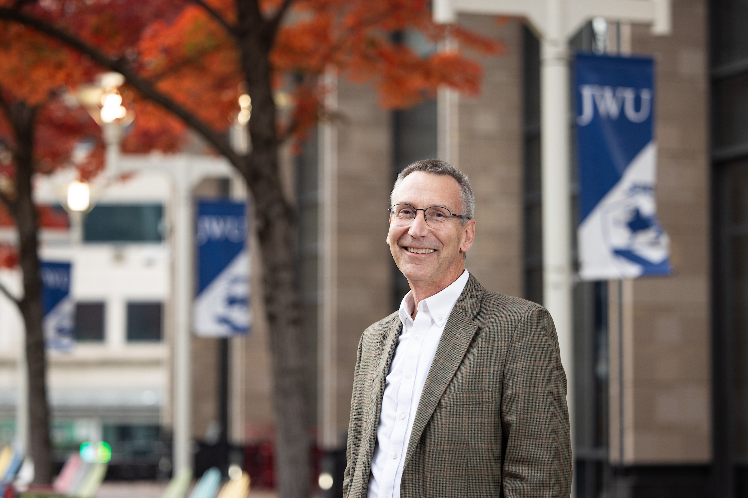 Charlotte President Mathieu standing on campus with JWU banners in background