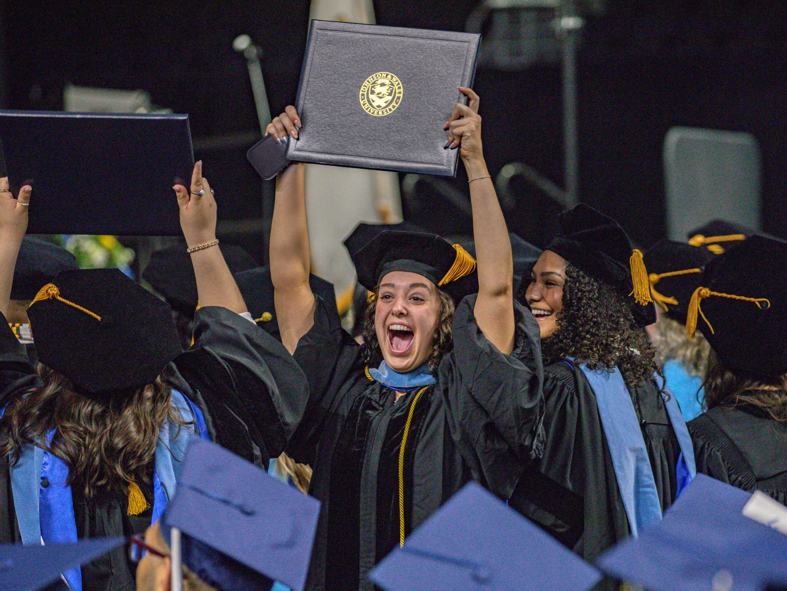 Excited graduate student holding up her degree at Johnson & Wales University's 2026 graduate commencement ceremony in Providence.