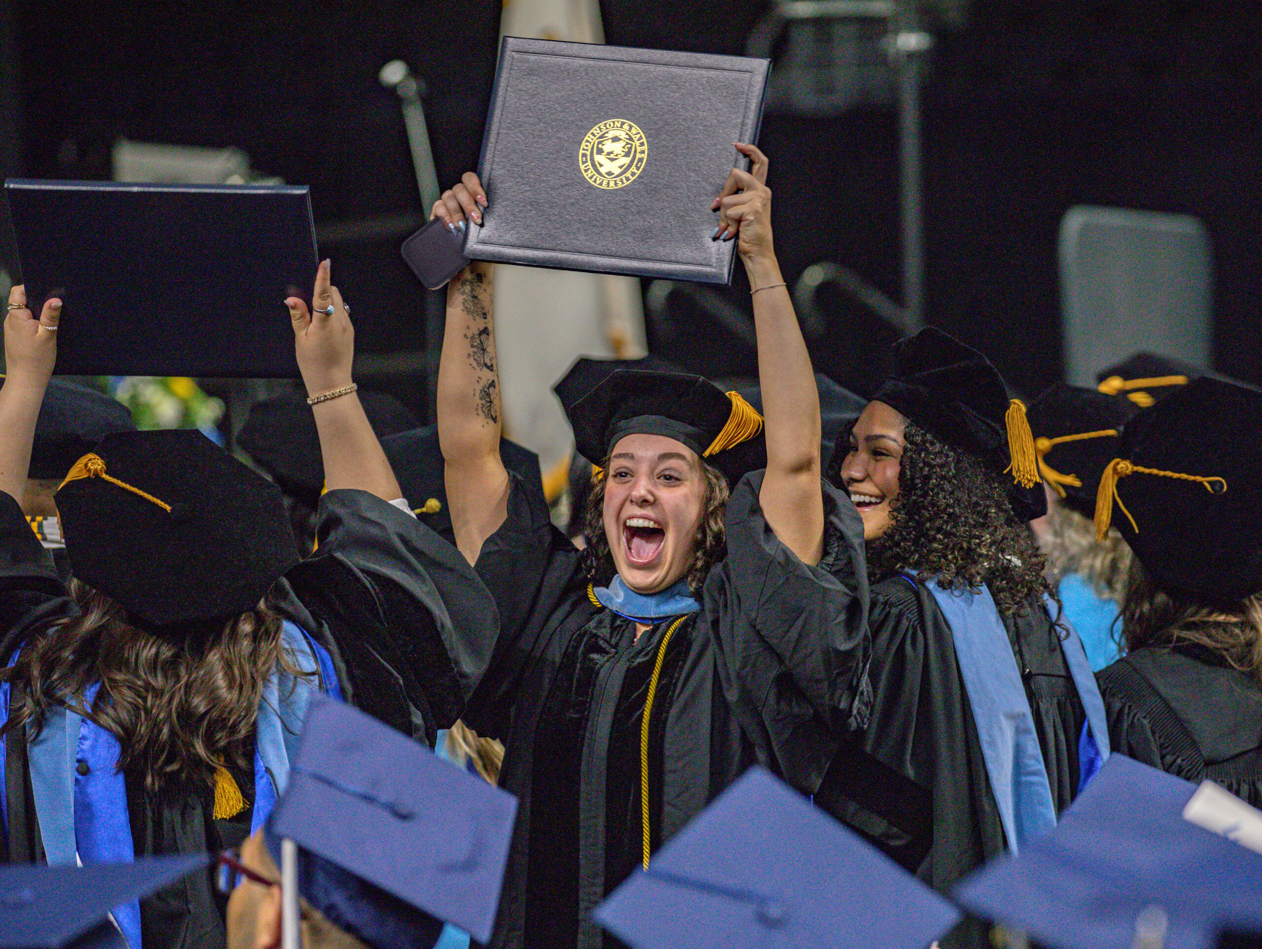 Excited graduate student holding up her degree at Johnson & Wales University's 2026 graduate commencement ceremony in Providence.