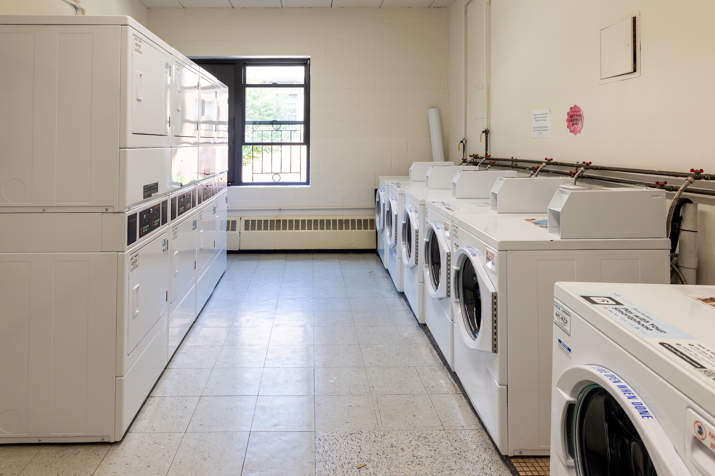 Laundry machines line the walls in a room.