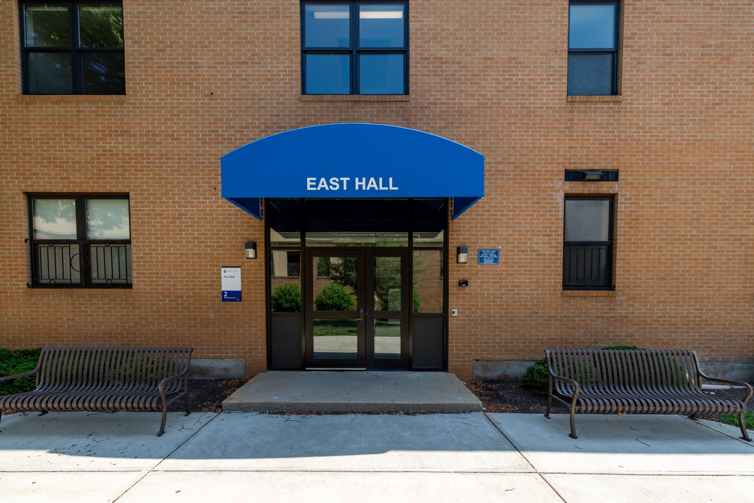 A residential life brick building with the words East Hall on a blue awning.