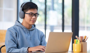 Student working on a laptop while wearing headphones.