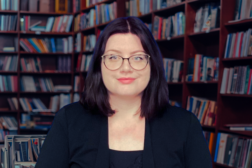 A person posing for a portrait in front a book shelf.