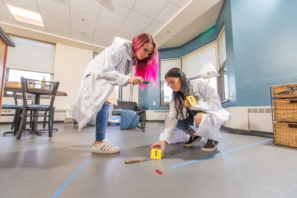two students investigating a mock crime scene at the JWU Criminal Justice Lab