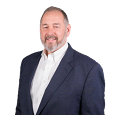 A person with a beard and short hair, wearing a dark suit jacket over a white collared shirt, smiles against a plain white background.