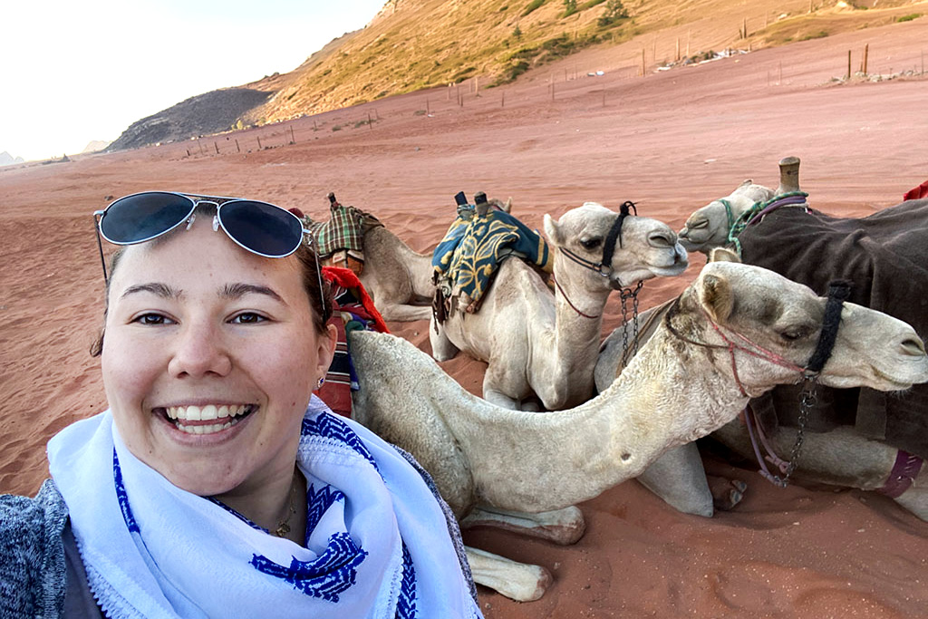 A person standing in front of camels.