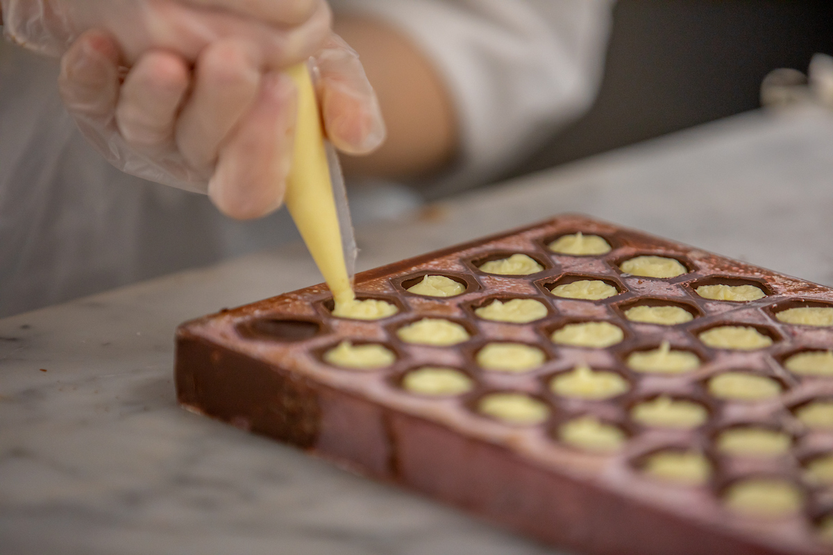 Baking and Pastry student uses a piping bag to fill chocolate molds.