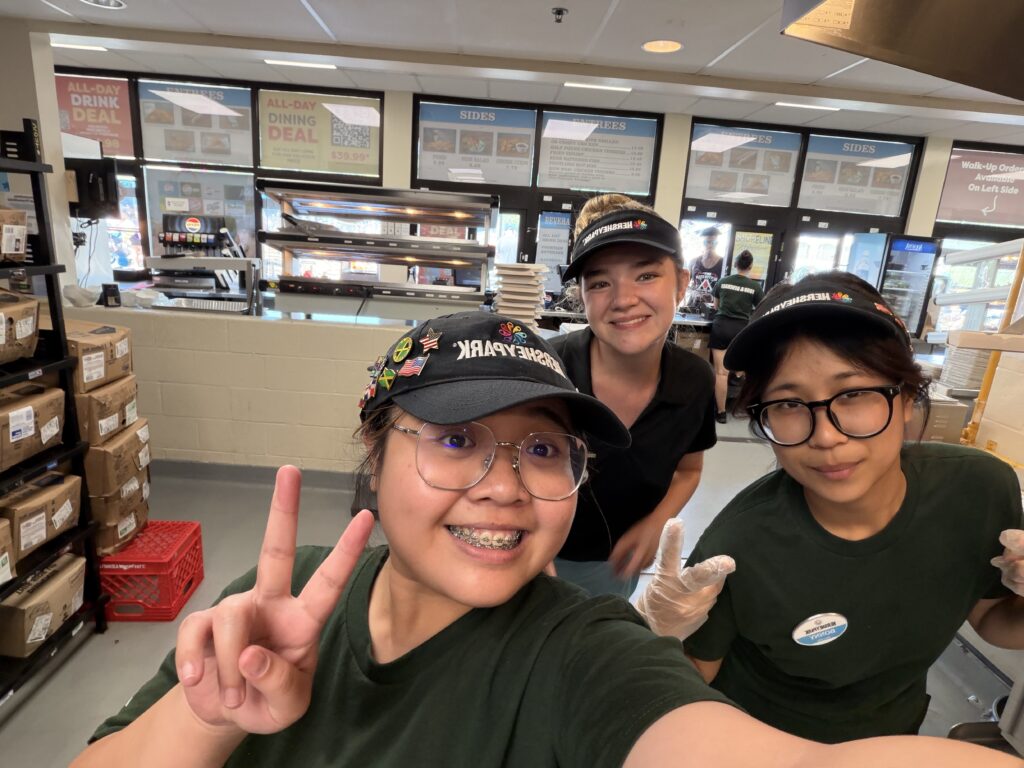 Three people wearing uniforms giving a peace sign to the camera.