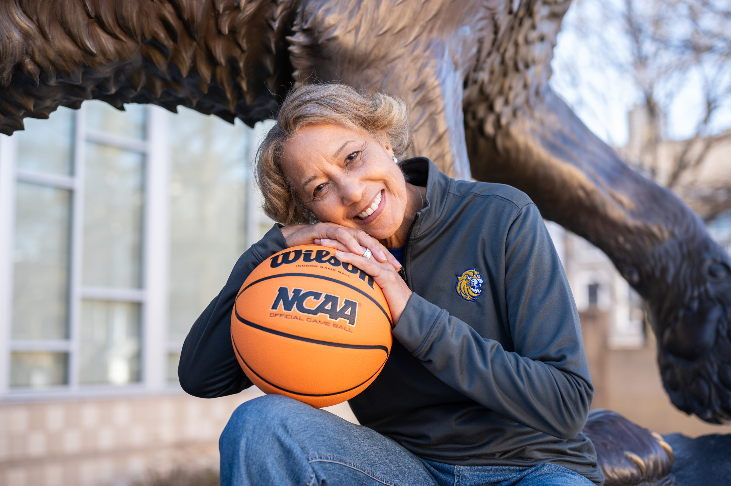 Trudi Lacey in front of the JWU Charlotte wildcat statue with a basketball in hand.