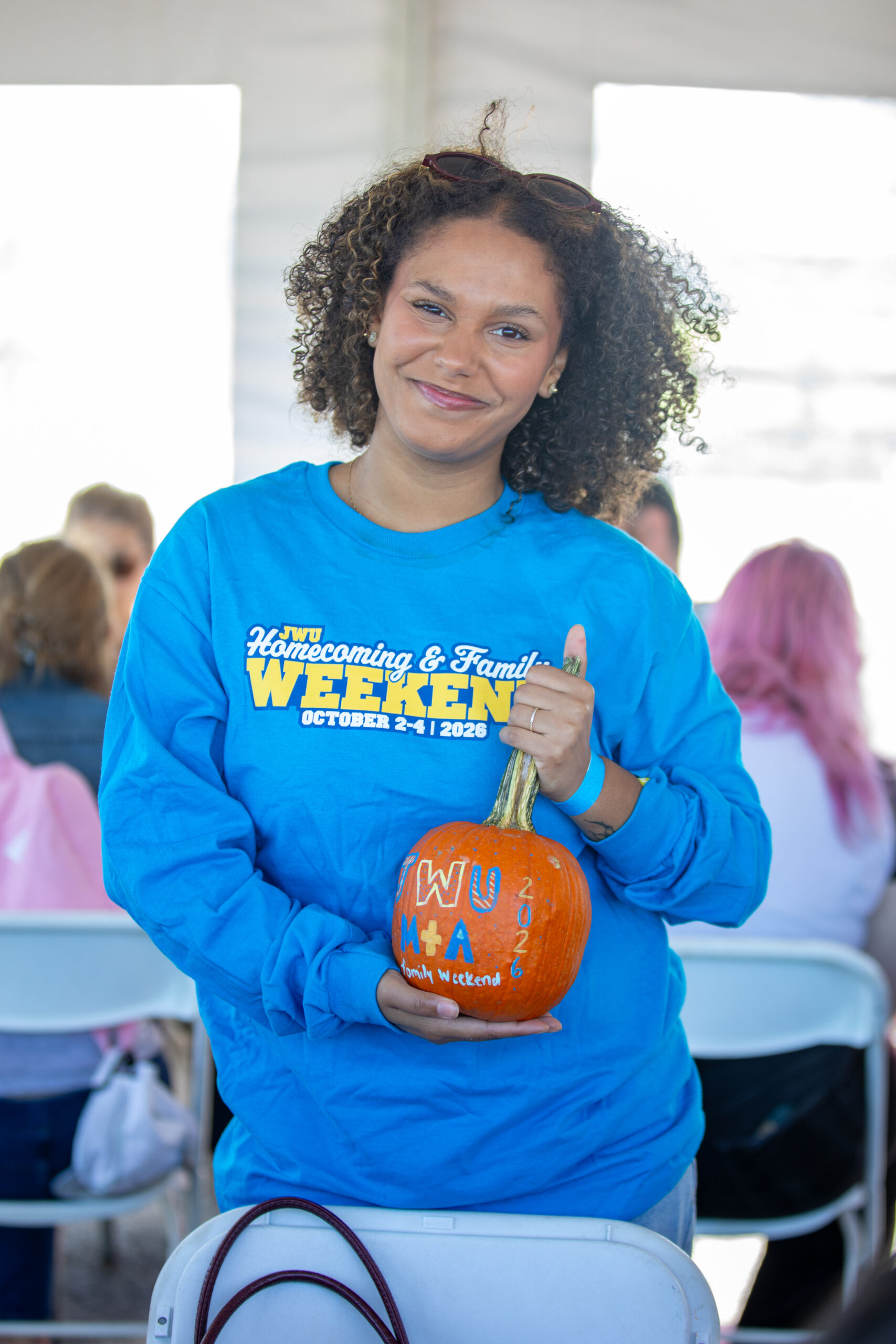 A person with curly hair, wearing a blue "JWU Homecoming 