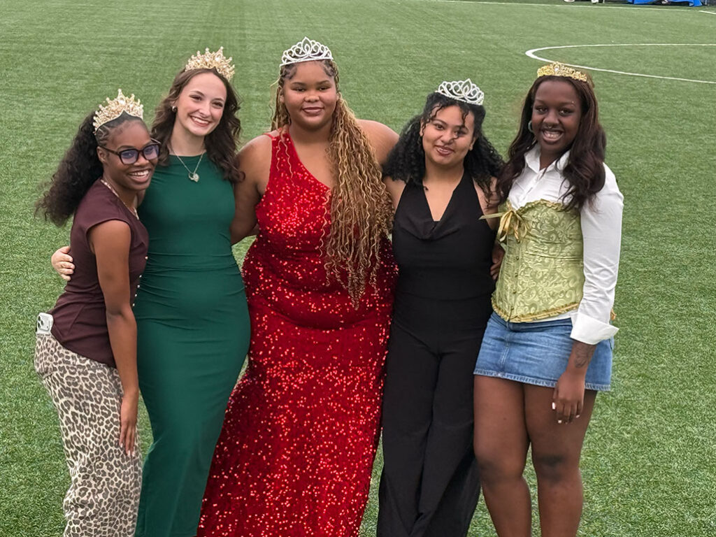 Five women posing while wearing tiaras