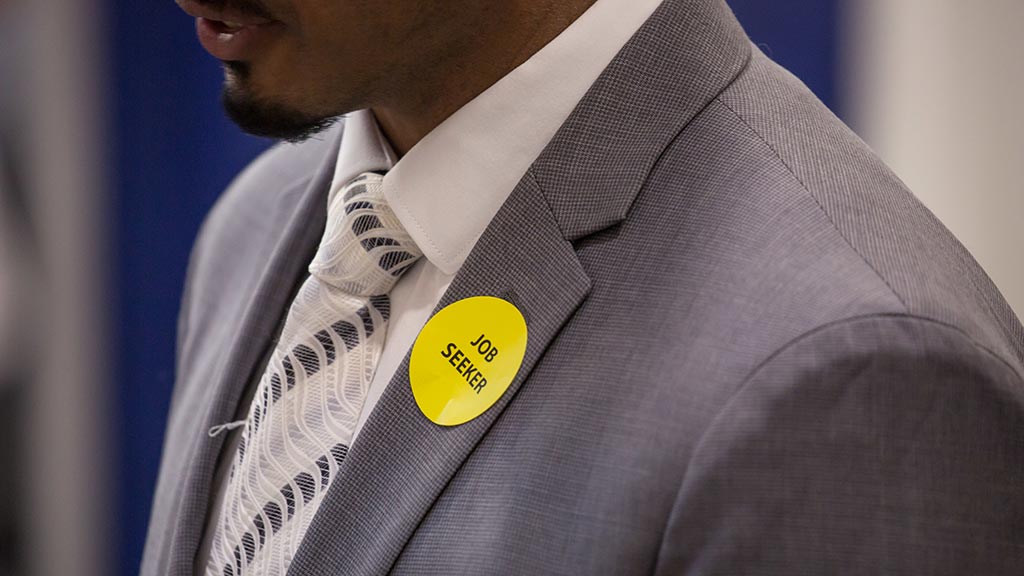 closeup photo of a sticker on the lapel of a young man's suit reading
