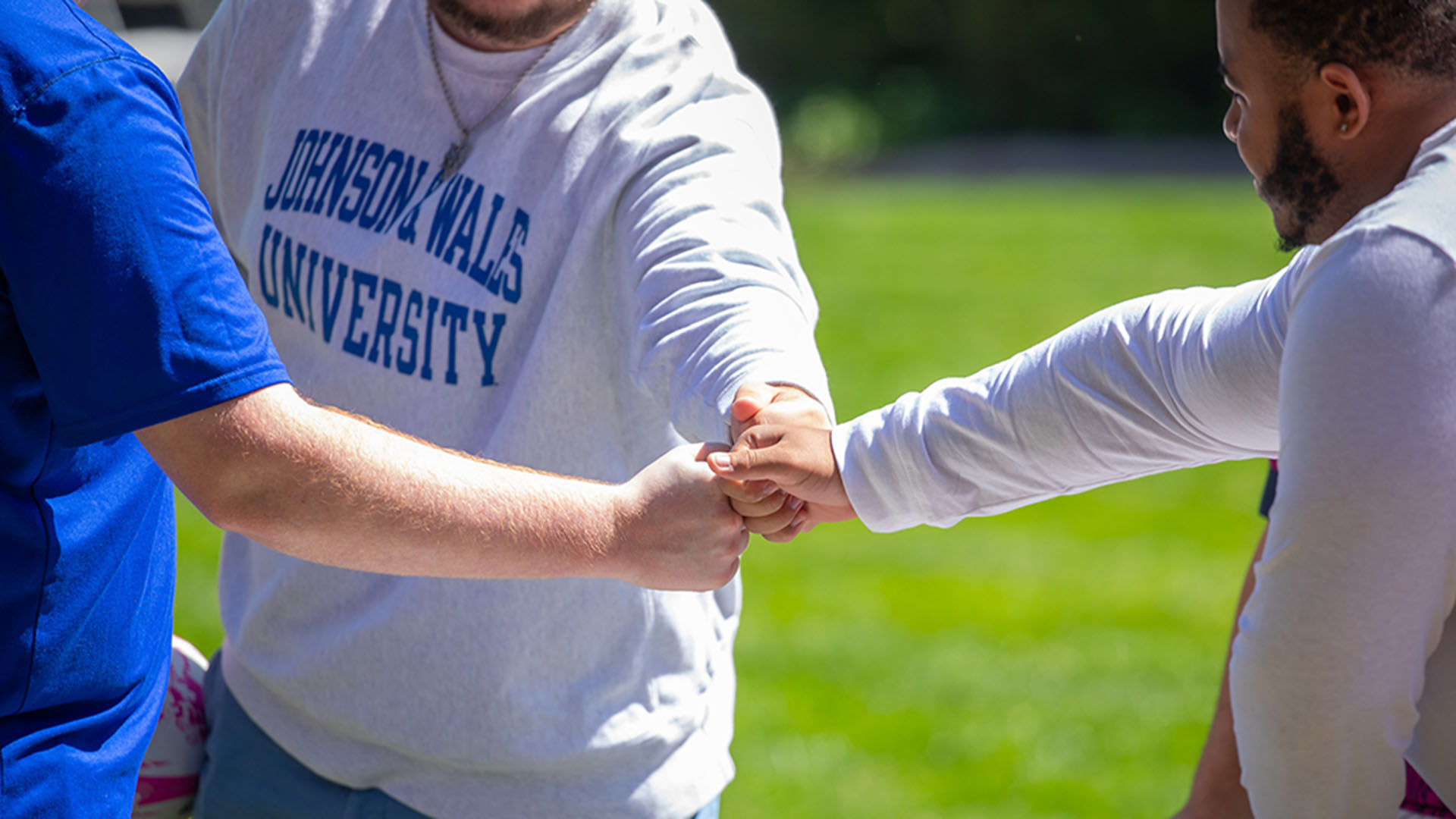 Three students fist bumping each other