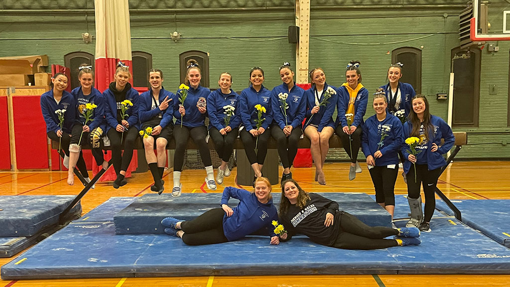 JWU gymnastics team posing on beam and mat