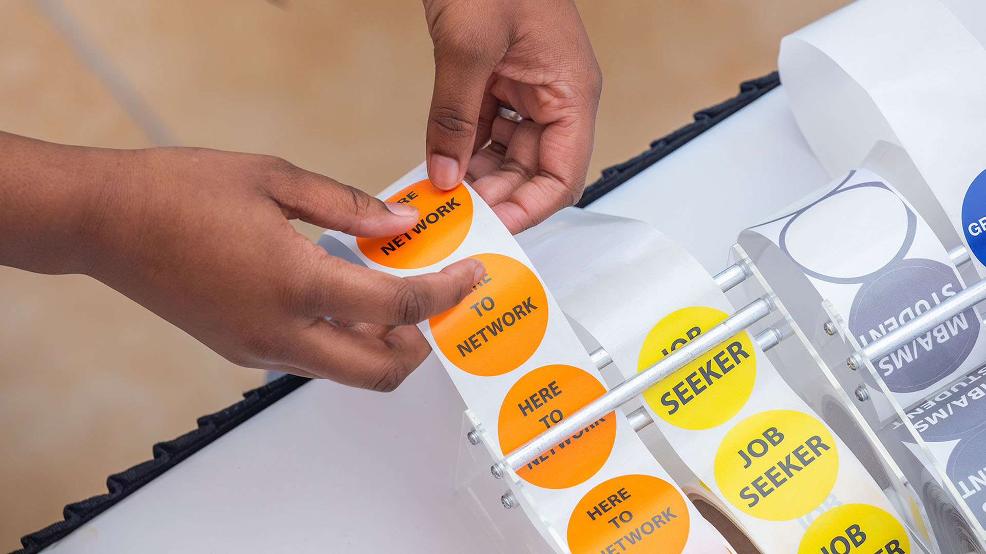 A person's hands reaching for an orange sticker that says u0022networkingu0022