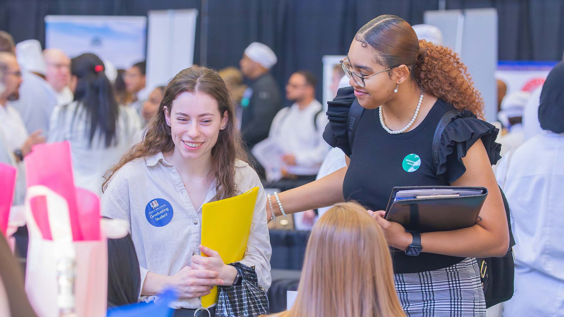 Two people exchanging a handshake at a Johnson u0026 Wales Career Fair.