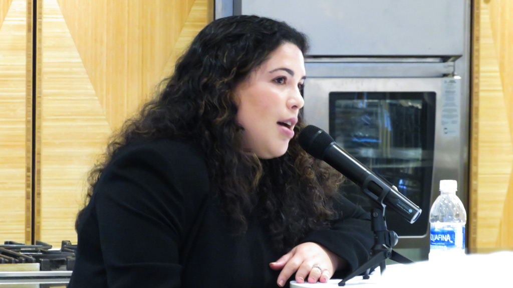 action photo of Maggie Pearson '13 addressing student at a microphone