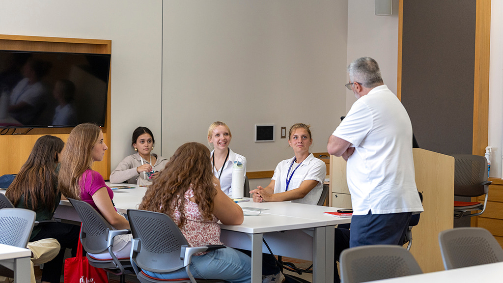 A professor lectures to a seated group of Health & Wellness CX students