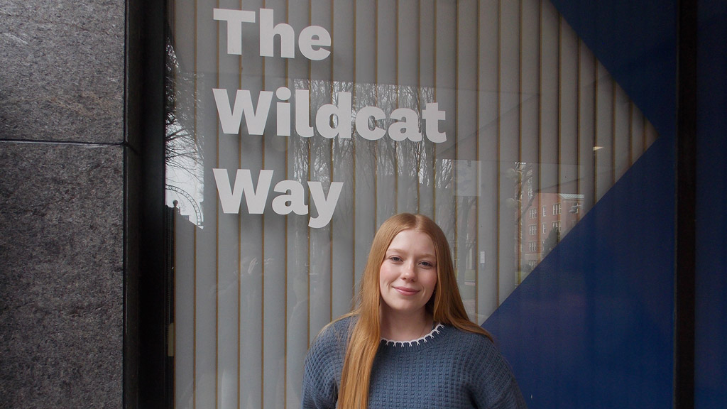 Katie McPartlin '28 stands under the words