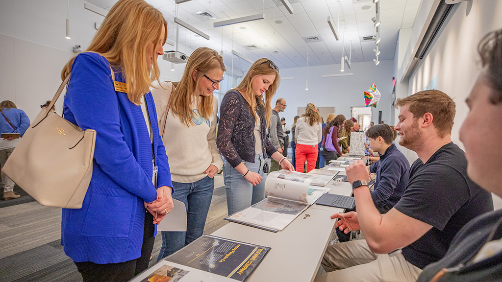 Students presenting portfolios at REVEAL Showcase