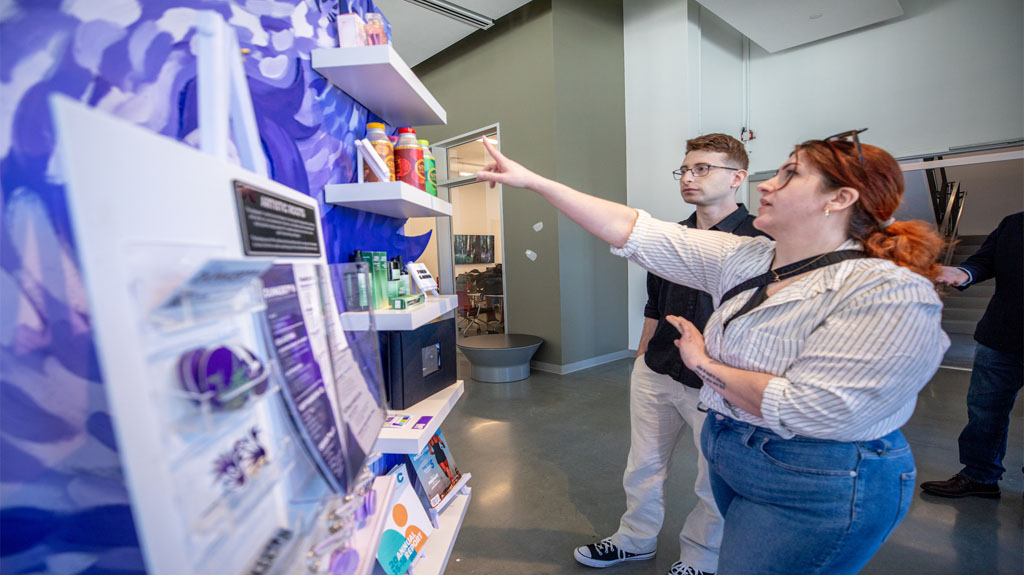 Student showing project board to attendee